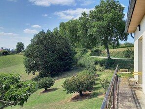 A balcony with a view of a green landscape, including trees and a grassy hill. - Agréable Maison Toute Équipée Classée 3 à Durfort Lacapelette (Durfort Lacapelette)