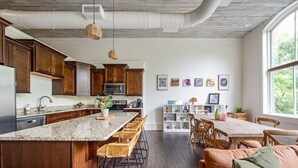 A modern kitchen with wooden cabinets, a granite countertop, and a central island with bar stools.
