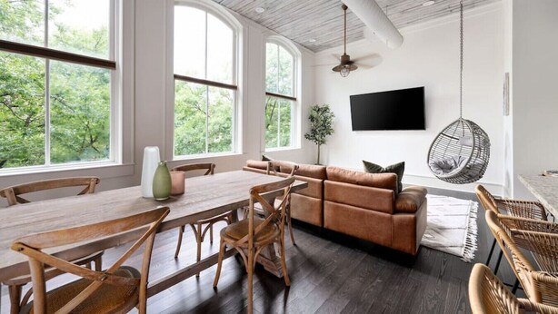 A spacious room with a wooden dining table, a brown sofa, and wicker chairs.