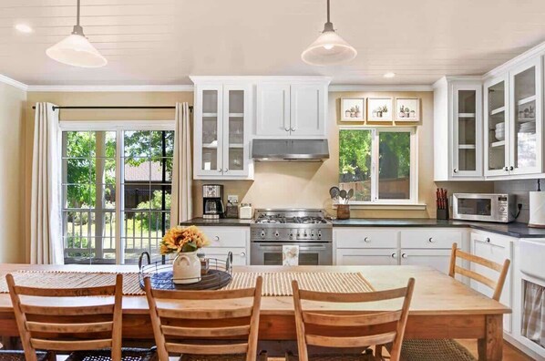 A kitchen with white cabinets, a stove, and a dining table with chairs.