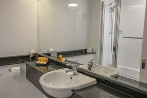 A modern bathroom with a large mirror, two sinks, a shower, and toiletries on the counter. - Normanton Park Hotel, Sure Hotel Collection by Bes (Oakham)