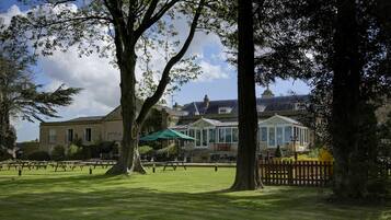 A large building with a green umbrella, a picnic table, and a wooden fence.