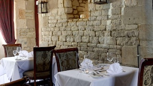 A stone-walled dining area with tables set for two, featuring classic chairs and a chandelier. - Normanton Park Hotel, Sure Hotel Collection by Bes (Oakham)