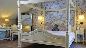 A four-poster bed with a mirror, floral wallpaper, bedside lamps, and a small bedside table with a telephone. - Normanton Park Hotel, Sure Hotel Collection by Bes (Oakham)