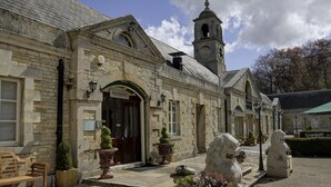 A stone building with a reception area, a bell tower, and stone lion statues. - Normanton Park Hotel, Sure Hotel Collection by Bes (Oakham)