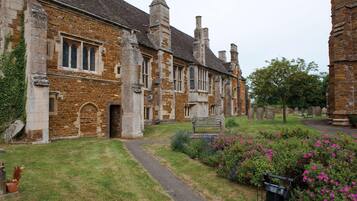 A historic stone building with a paved pathway leading to a bench.