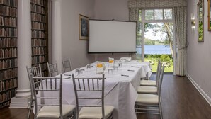 A conference room with a white table, chairs, a projector screen, and a view of a lake. - Normanton Park Hotel, Sure Hotel Collection by Bes (Oakham)