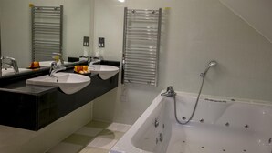A modern bathroom with a large bathtub, two sinks, and a towel rack. - Normanton Park Hotel, Sure Hotel Collection by Bes (Oakham)