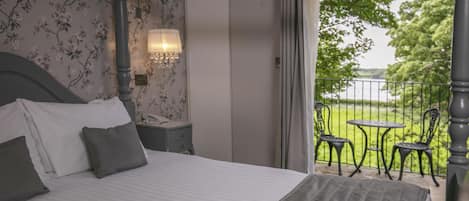 A bedroom with a bed, a nightstand, a lamp, and a view of an outdoor patio with chairs and a table.