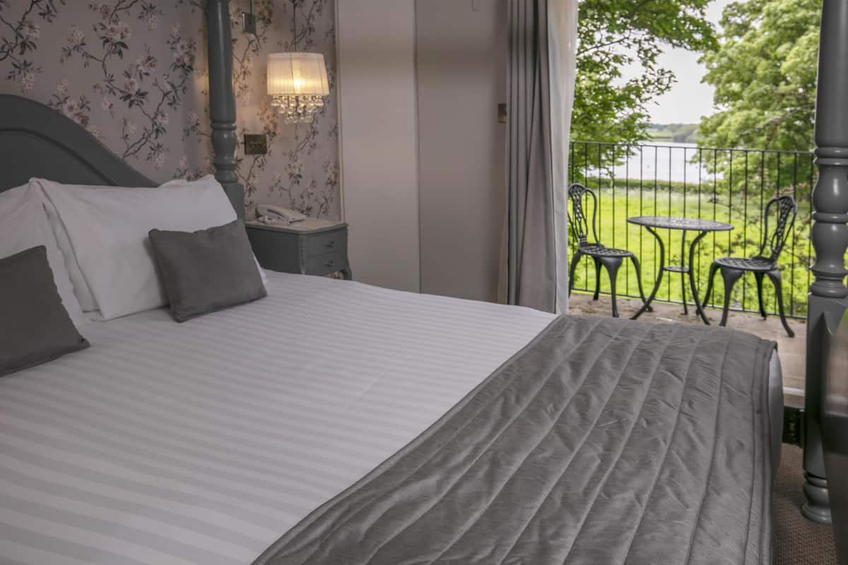 A bedroom with a bed, a nightstand, a lamp, and a view of an outdoor patio with chairs and a table.
