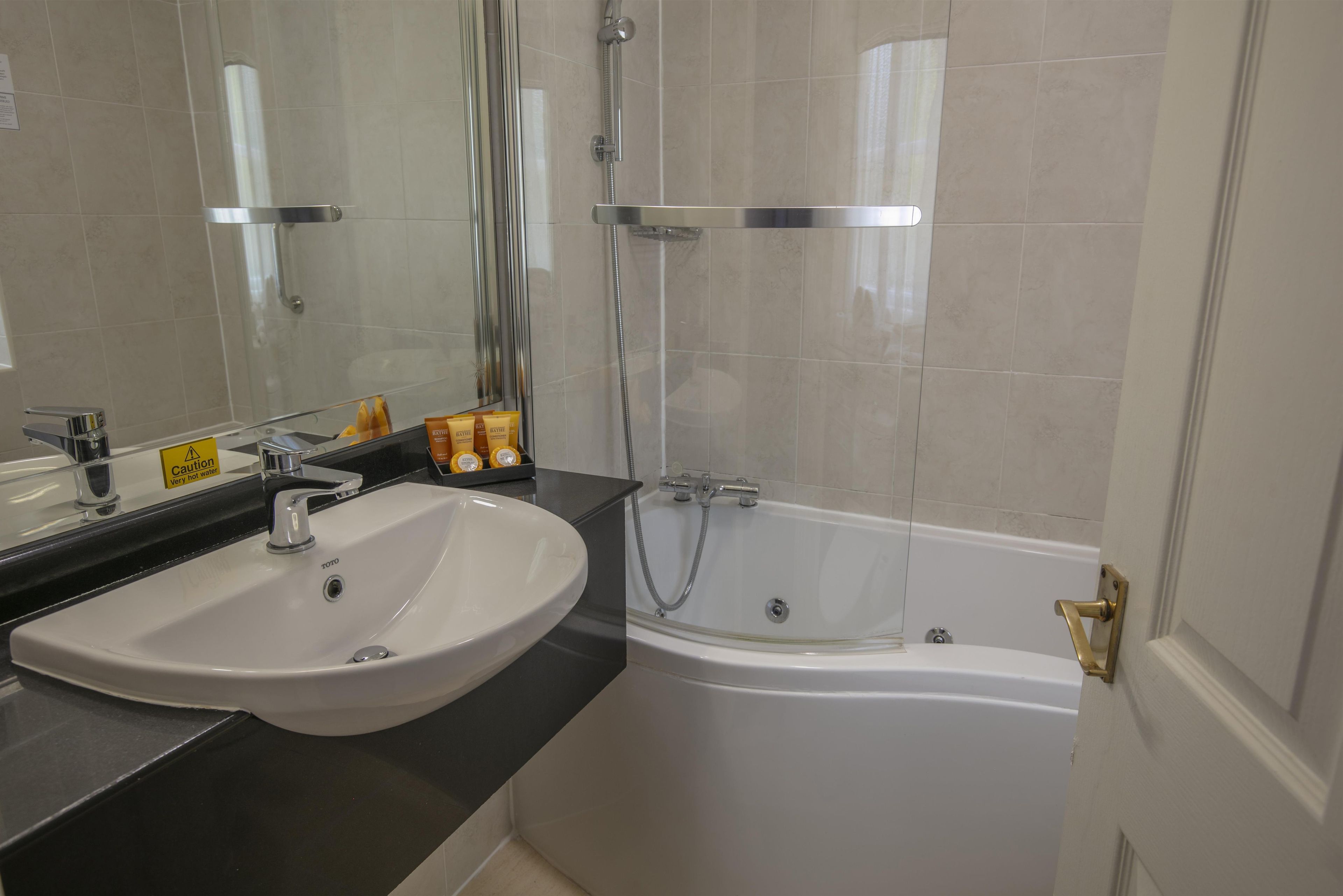 Une salle de bain avec un lavabo blanc, une baignoire et une cabine de douche en verre.