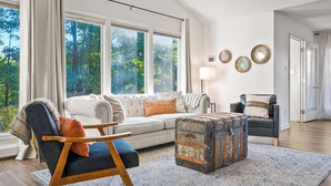 A living room with a sofa, a chair, a lamp, and a vintage suitcase.