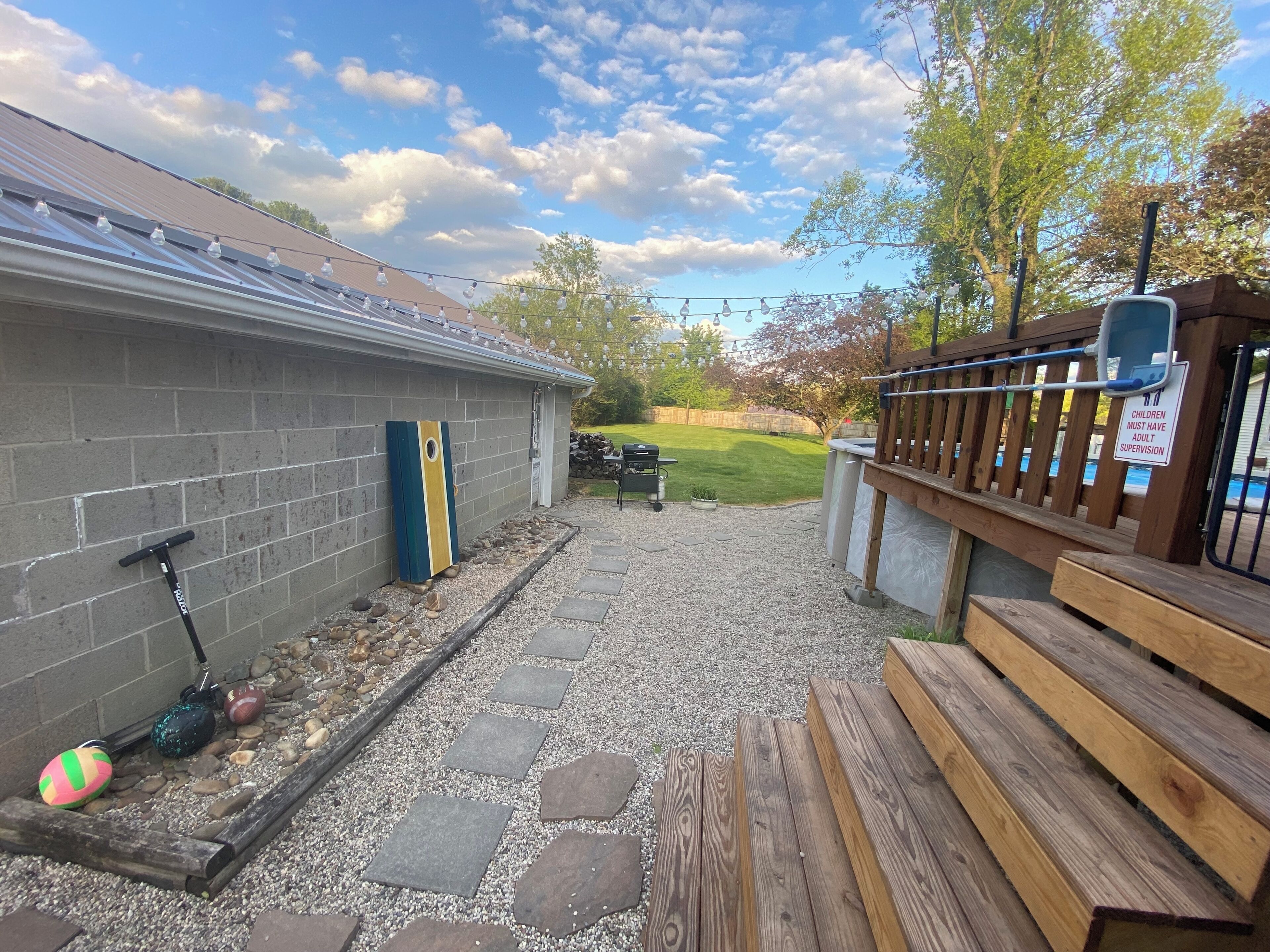 Un patio trasero con terraza, una cubierta de madera y una zona de piscina.
