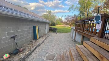 Un patio trasero con terraza, una cubierta de madera y una zona de piscina.