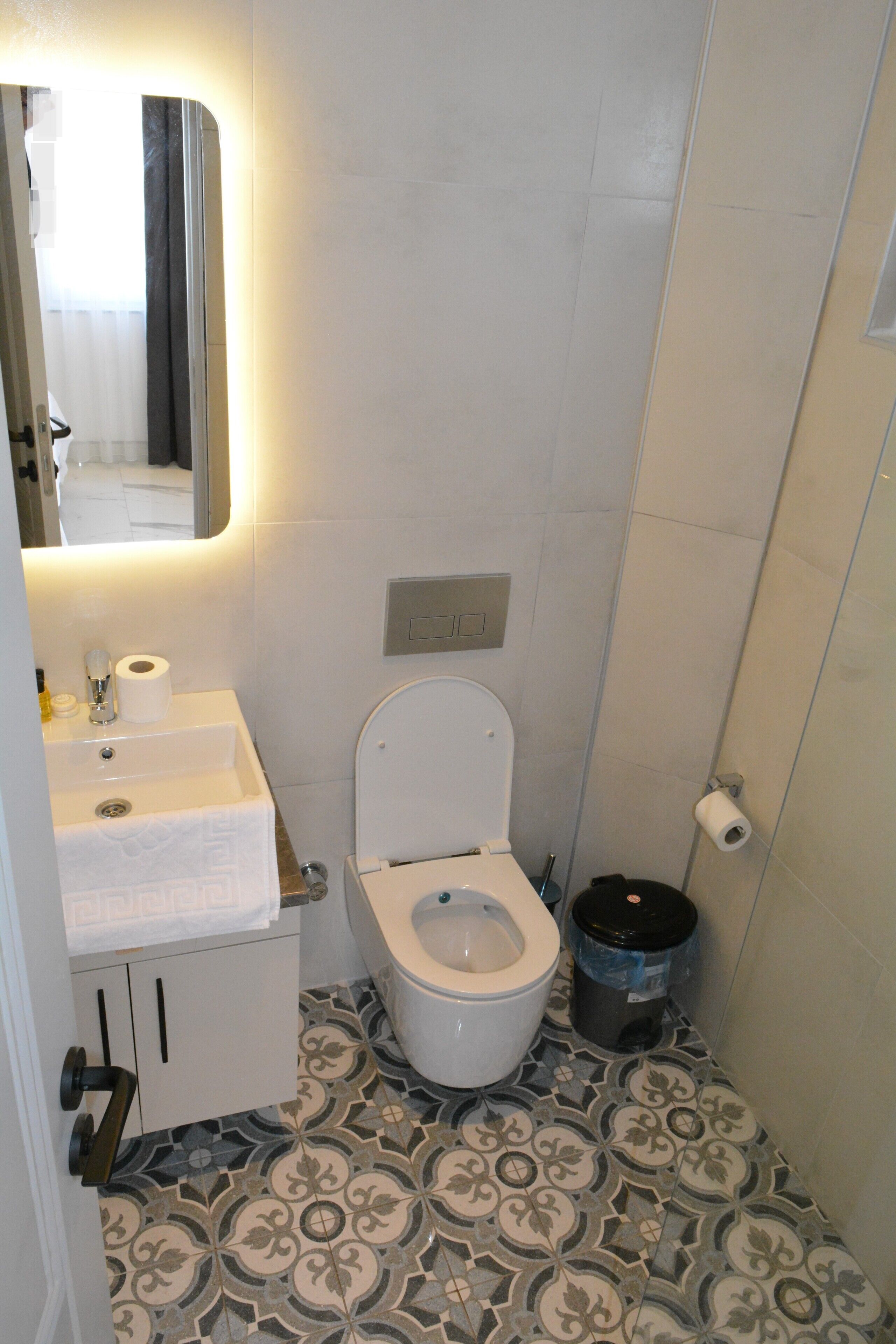 Un baño con inodoro, lavabo y baldosas de suelo con diseño.