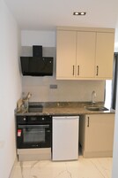 Una cocina compacta con horno integrado, microondas y un refrigerador pequeño.