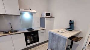 Moderni keittiö, jossa on sisäänrakennettu uuni, mikroaaltouuni ja kahvinkeitin pienellä keittiösaarekkeella.