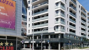 Un immeuble à plusieurs étages doté de balcons, un ciel dégagé et une rue en contrebas.