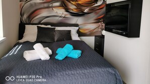 Une chambre d’hôtel avec un lit, une télévision et une fresque murale.