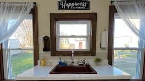 A kitchen with a large island, a window, and a sign that says "Happiness is homemade." - The (Veteran Owned) Hanover Hangout Guesthouse - cozy cottage w/ privacy + fun (Hanover)