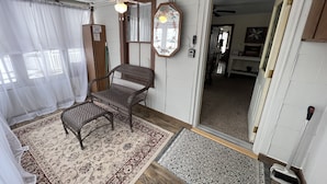 A cozy room with a wicker chair, a patterned rug, and a wooden floor. - The (Veteran Owned) Hanover Hangout Guesthouse - cozy cottage w/ privacy + fun (Hanover)