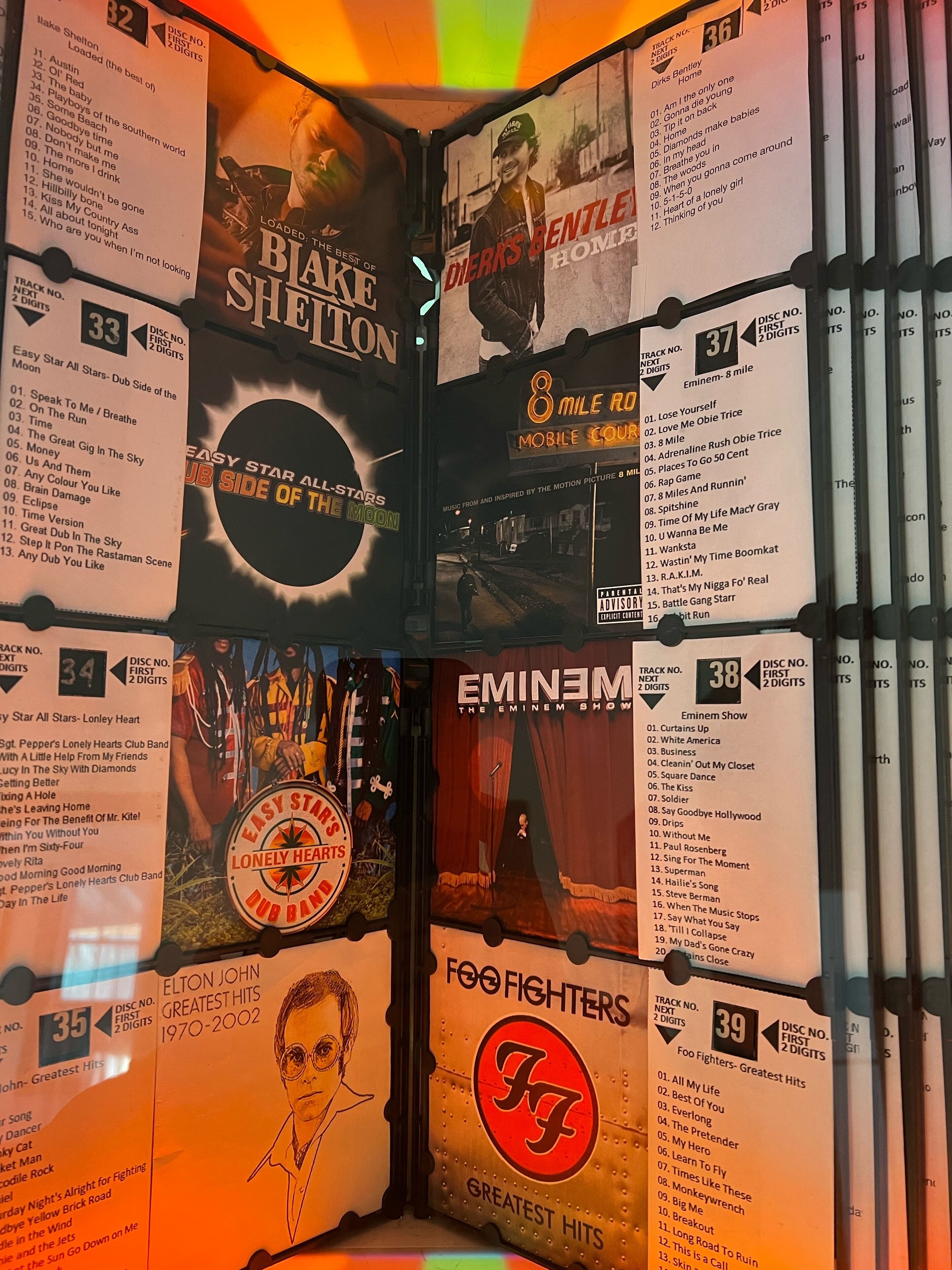 A wall with album covers and track lists, including artists like Eminem and Foo Fighters.
