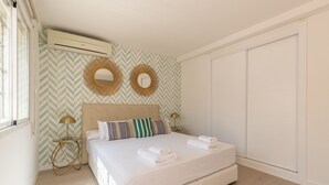 Ein ordentlich eingerichtetes Schlafzimmer mit einem Bett, zwei Wandspiegeln, einem Nachttisch mit Lampe und einem Kleiderschrank.