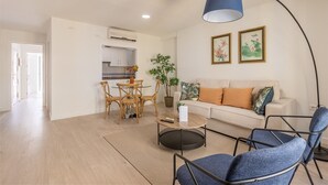 Ein modernes Wohnzimmer mit einem runden Couchtisch, einer Couch und einem Essbereich mit Tisch und Stühlen.
