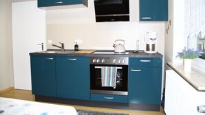 Una cocina moderna con armarios color turquesa, horno empotrado, microondas y cafetera.