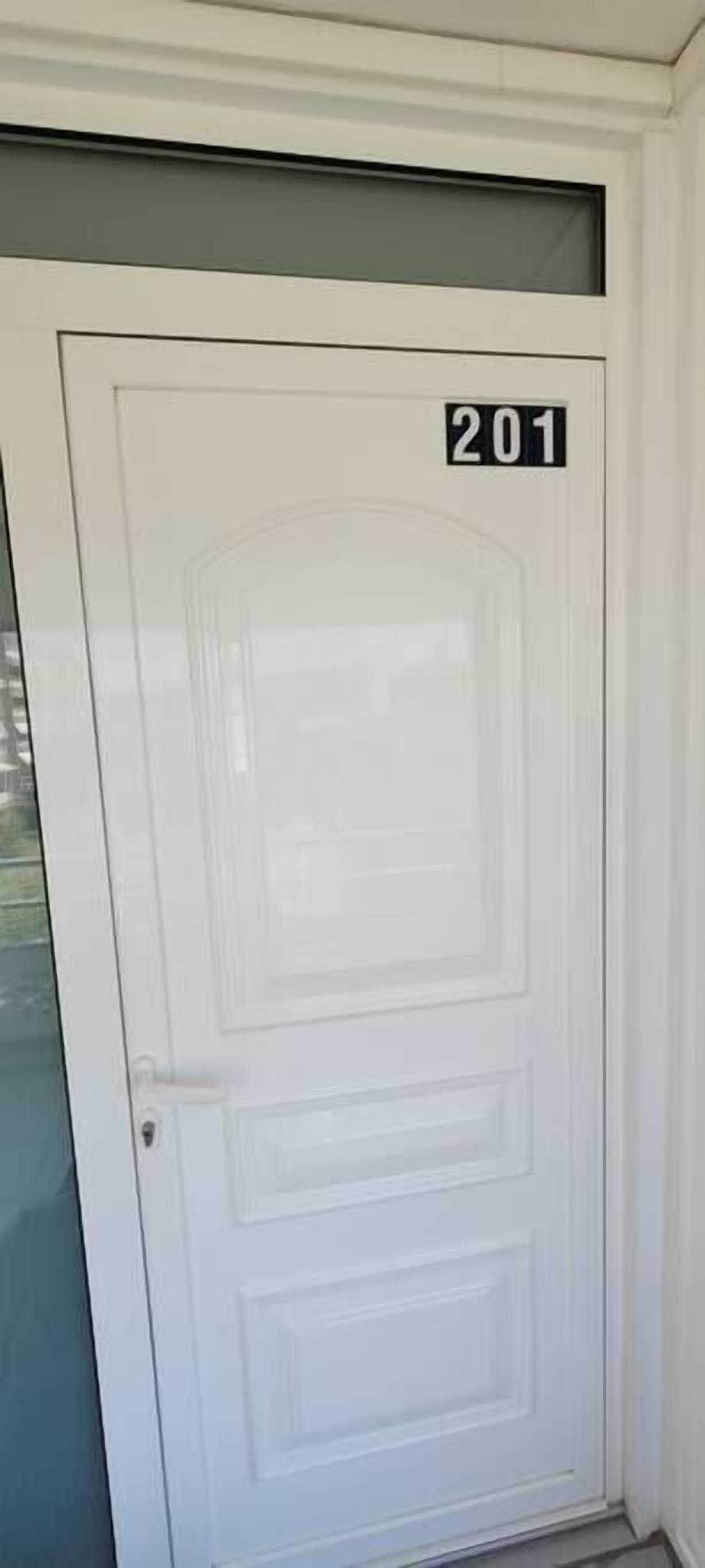 Una puerta blanca con una placa que indica el número '201' y un panel de vidrio arriba.