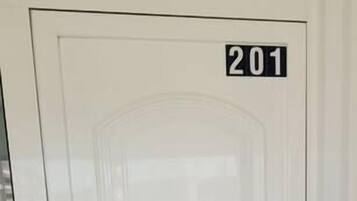 Una puerta blanca con una placa que indica el número '201' y un panel de vidrio arriba.
