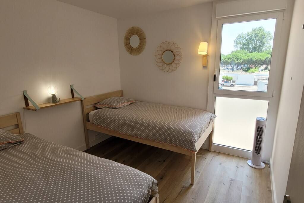 Une chambre avec deux lits, une fenêtre, un radiateur et des éléments de décoration murale.