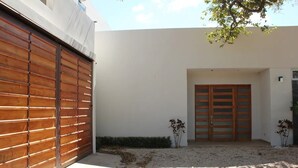 Un bâtiment moderne à l’extérieur blanc, doté d’une porte de garage en bois et d’une double porte d’entrée en bois.