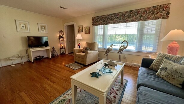 A living room with a television, a sofa, a coffee table, and a window with blinds. - Cozy Cottage in quiet neighborhood not far from beaches (Marshallberg)