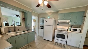 A kitchen with teal cabinets, a white refrigerator, a stove, and a microwave. - Cozy Cottage in quiet neighborhood not far from beaches (Marshallberg)