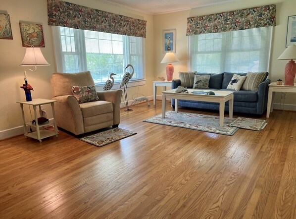 Un salon avec un fauteuil beige, un canapé bleu, une table basse blanche et un tapis à motifs.