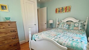 A bedroom with a white bed, wooden dresser, and a ceiling fan. - Cozy Cottage in quiet neighborhood not far from beaches (Marshallberg)