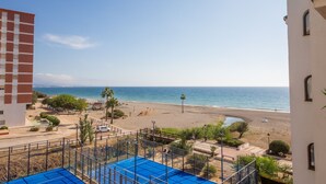 A beach view from a balcony with a pool area in the foreground. - Marina de la Duquesa 1031 (Manilva)
