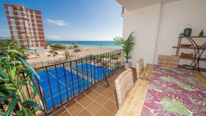 A balcony with a view of a beach and a swimming pool. - Marina de la Duquesa 1031 (Manilva)