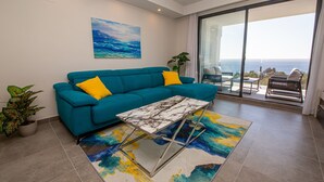 A modern living room with a teal sofa, a marble coffee table, and a colorful abstract rug. - Blue Suites apto B5-203 (Manilva)