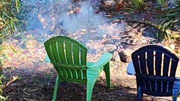 Two chairs by a small body of water with rocks and plants around.