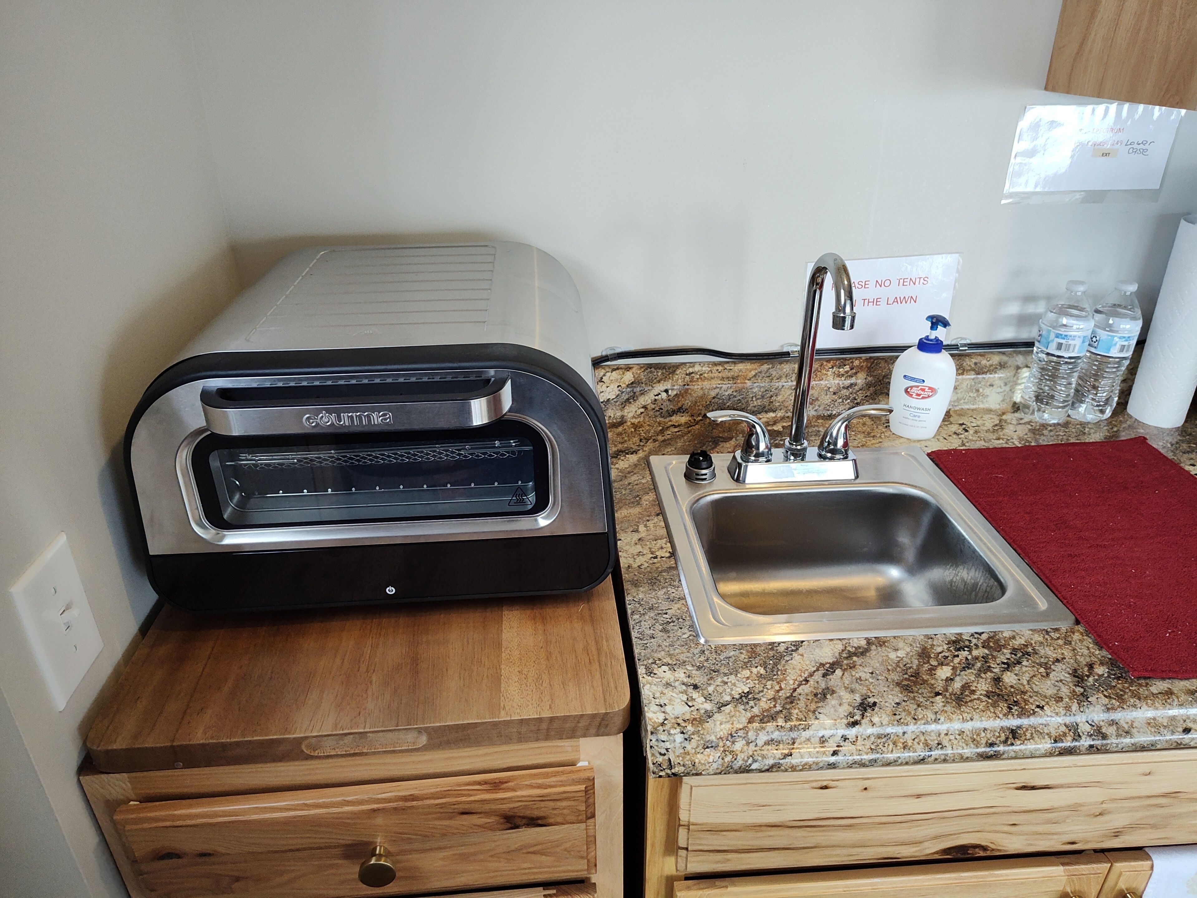 A kitchen with a built-in oven, stainless steel sink, and granite countertop.