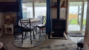 A cozy room with a fireplace, a dining table with chairs, a TV, and a view of the outdoors.