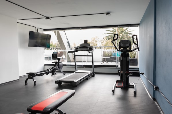 Ein modernes Fitnessstudio mit Laufband, Bank und Kraftgerät.