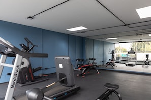 Un gimnasio con cintas de correr, mancuernas y equipamiento de ejercicio.