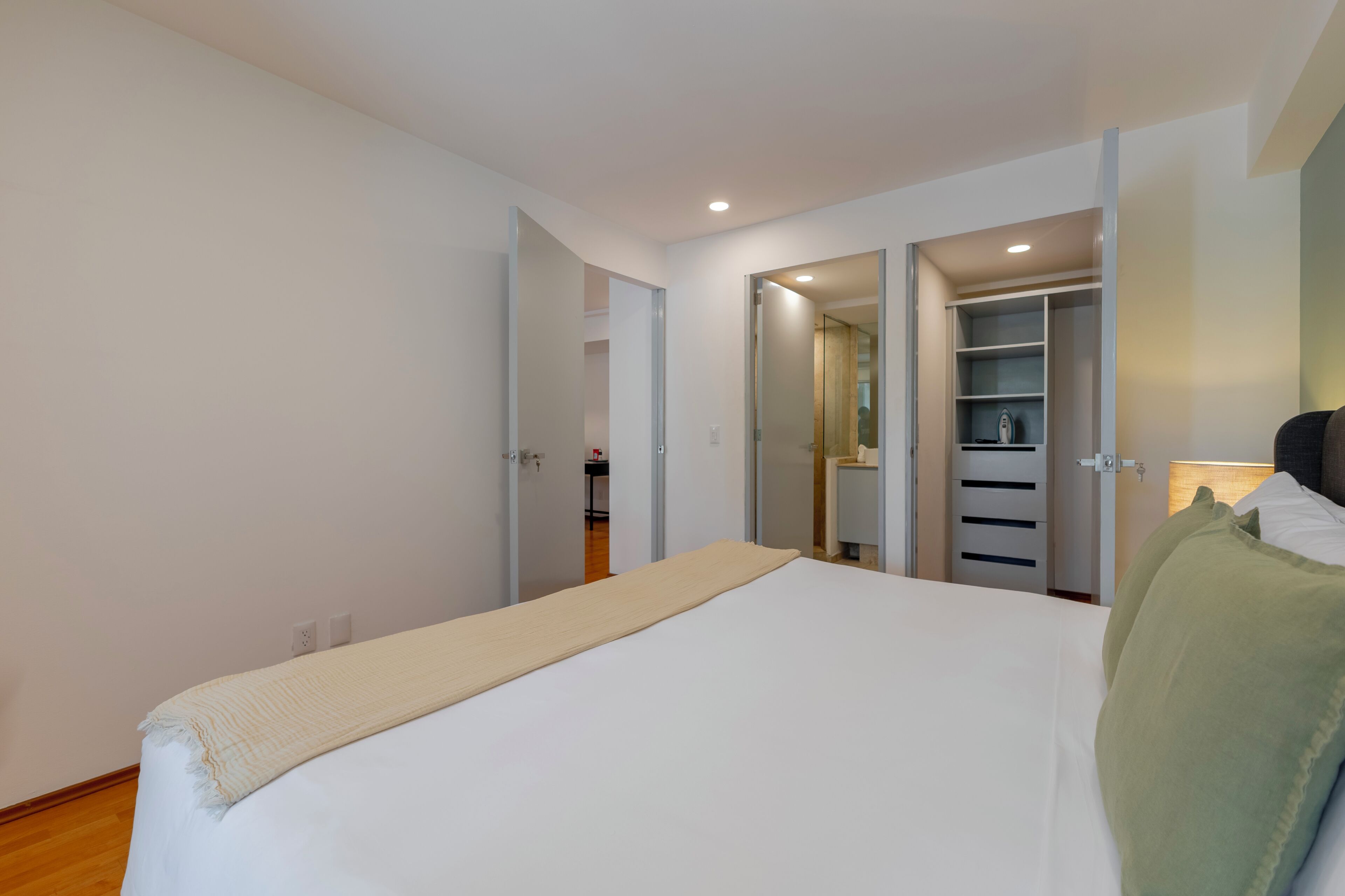 A bedroom with a bed, a bedside table, a wardrobe, and a mirror.