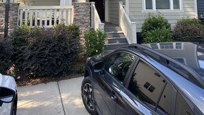 A two-story house with a front porch, a balcony, and a garage. - Gorgeous 3 bedroom house with patio and firepit (Charlotte)