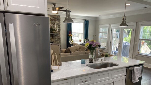 A modern kitchen with a stainless steel refrigerator, white cabinetry, a marble countertop, and pendant lighting. - Gorgeous 3 bedroom house with patio and firepit (Charlotte)