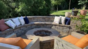 A stone fire pit surrounded by wicker furniture and cushions. - Gorgeous 3 bedroom house with patio and firepit (Charlotte)
