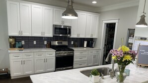 A modern kitchen with white cabinets, a stainless steel range, and a marble countertop. - Gorgeous 3 bedroom house with patio and firepit (Charlotte)